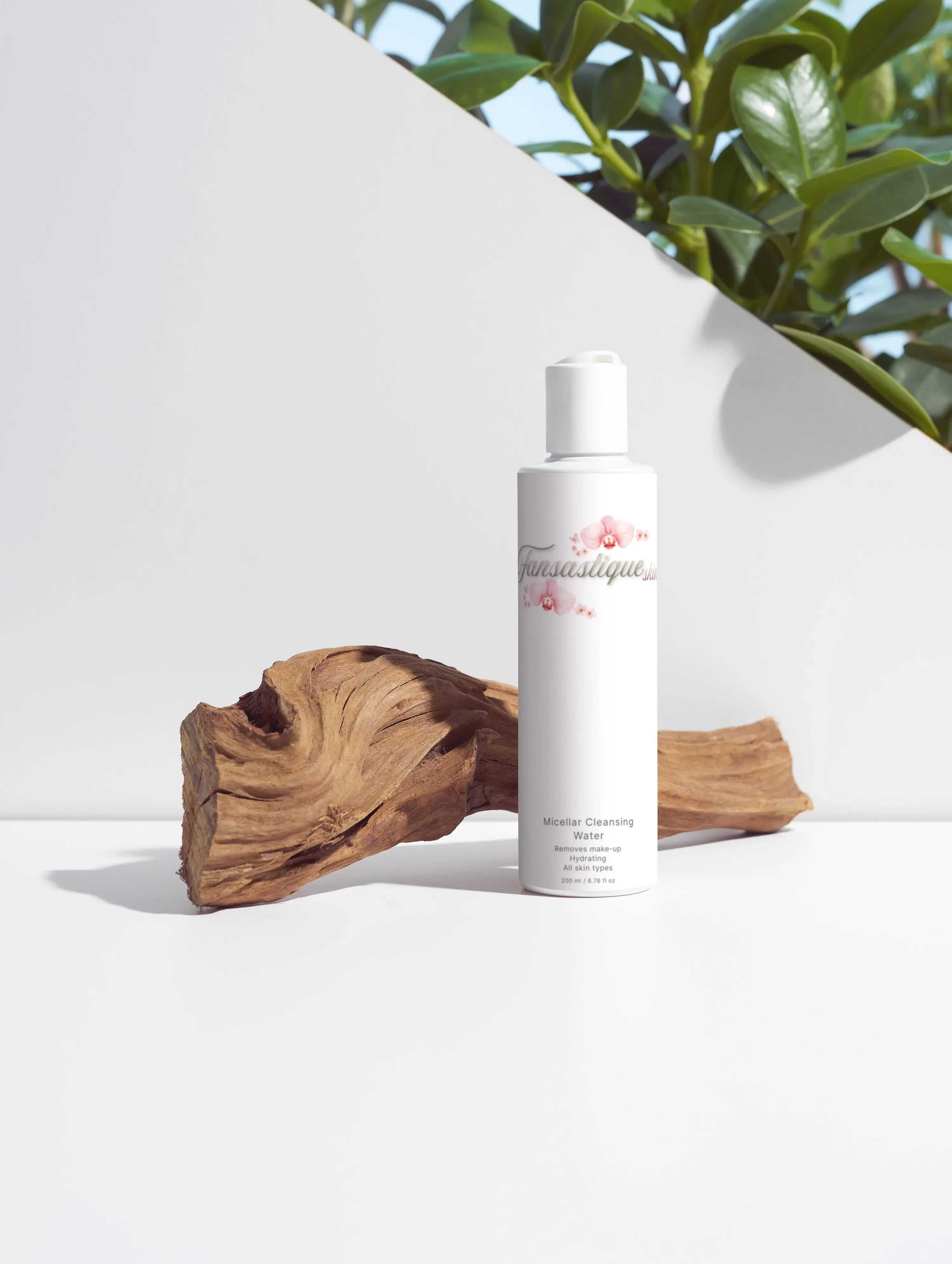 Micellar cleansing water fles voor de huidverzorging, met hout en groene bladeren op de achtergrond.